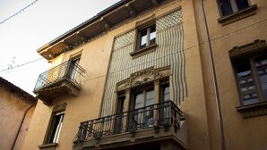 Un edificio con balcón, una ventana de marco decorativo y una guirnalda de luces.