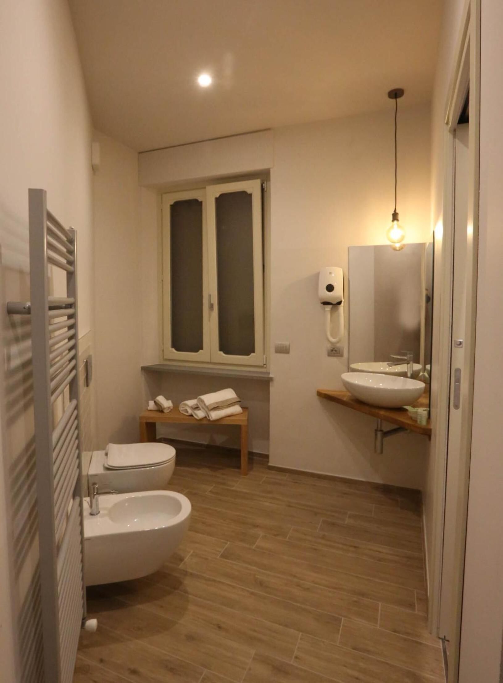 A compact bathroom with a toilet, bidet, and a sink with a mirror.