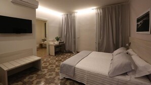 Una habitación de hotel con una cama, un escritorio, una silla, un televisor y un equipo de aire acondicionado.