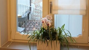 Una ventana con vistas a un balcón y una planta en maceta.
