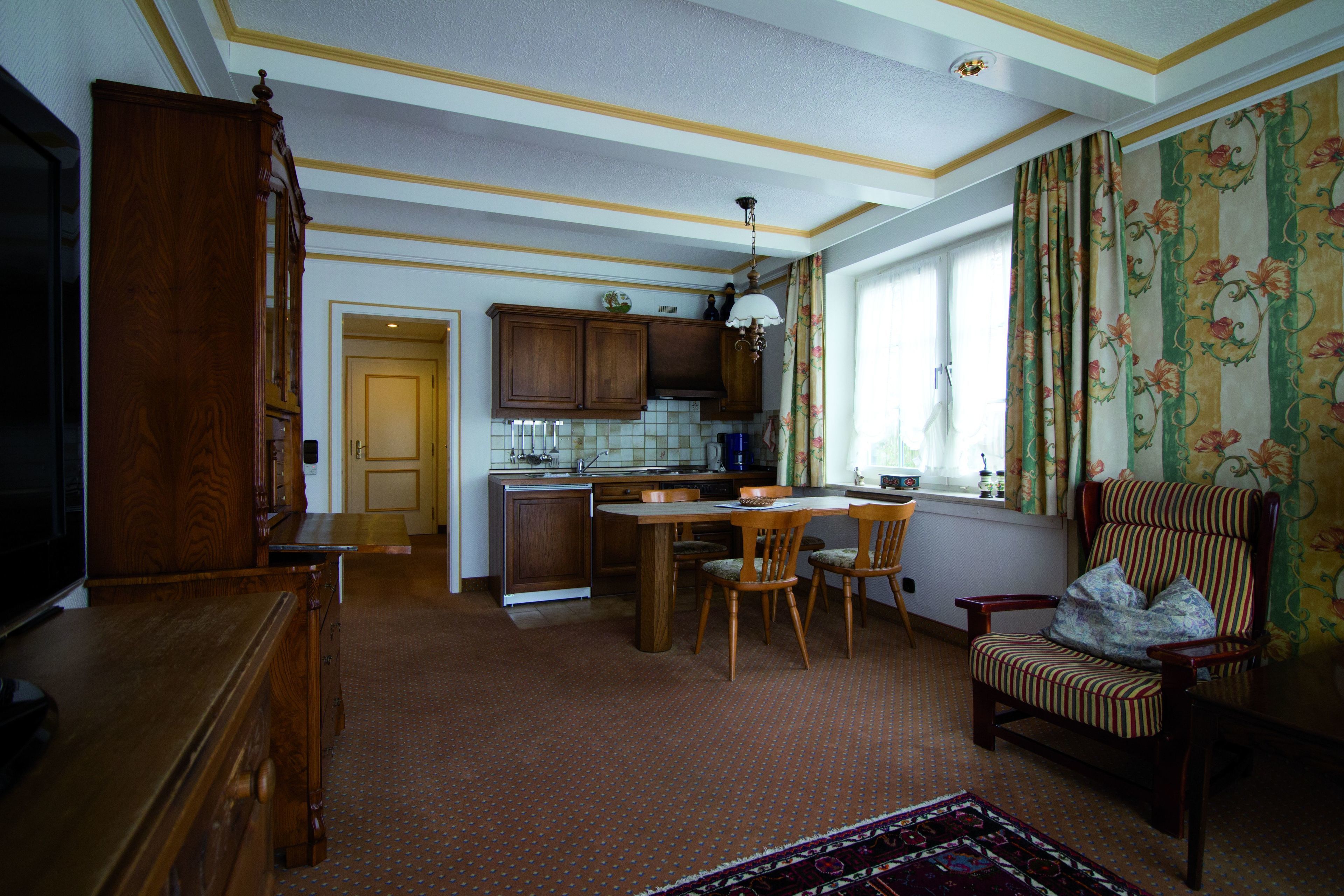 A spacious kitchen with wooden cabinets, a dining area with a table and chairs, a large wooden cabinet, and a television.
