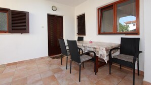 Ein Essbereich mit Tisch und vier Stühlen, einer Uhr an der Wand und einer Tür mit Fenster.