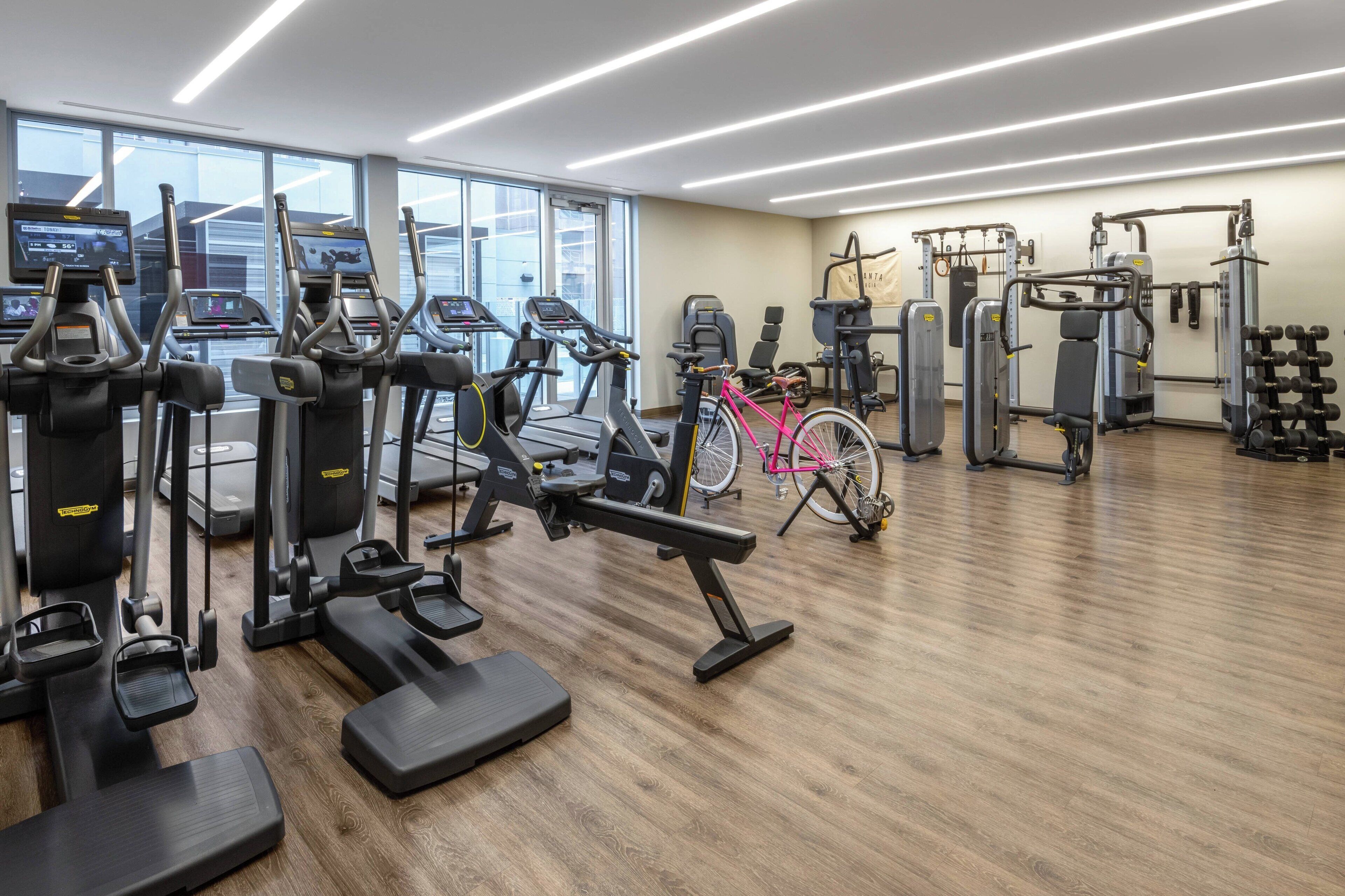 A modern gym with treadmills, elliptical machines, and weightlifting equipment.
