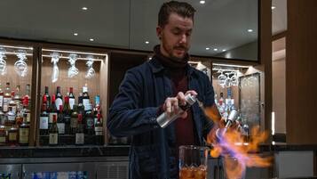 Een bartender bereidt een drankje toe met een brandende fles.