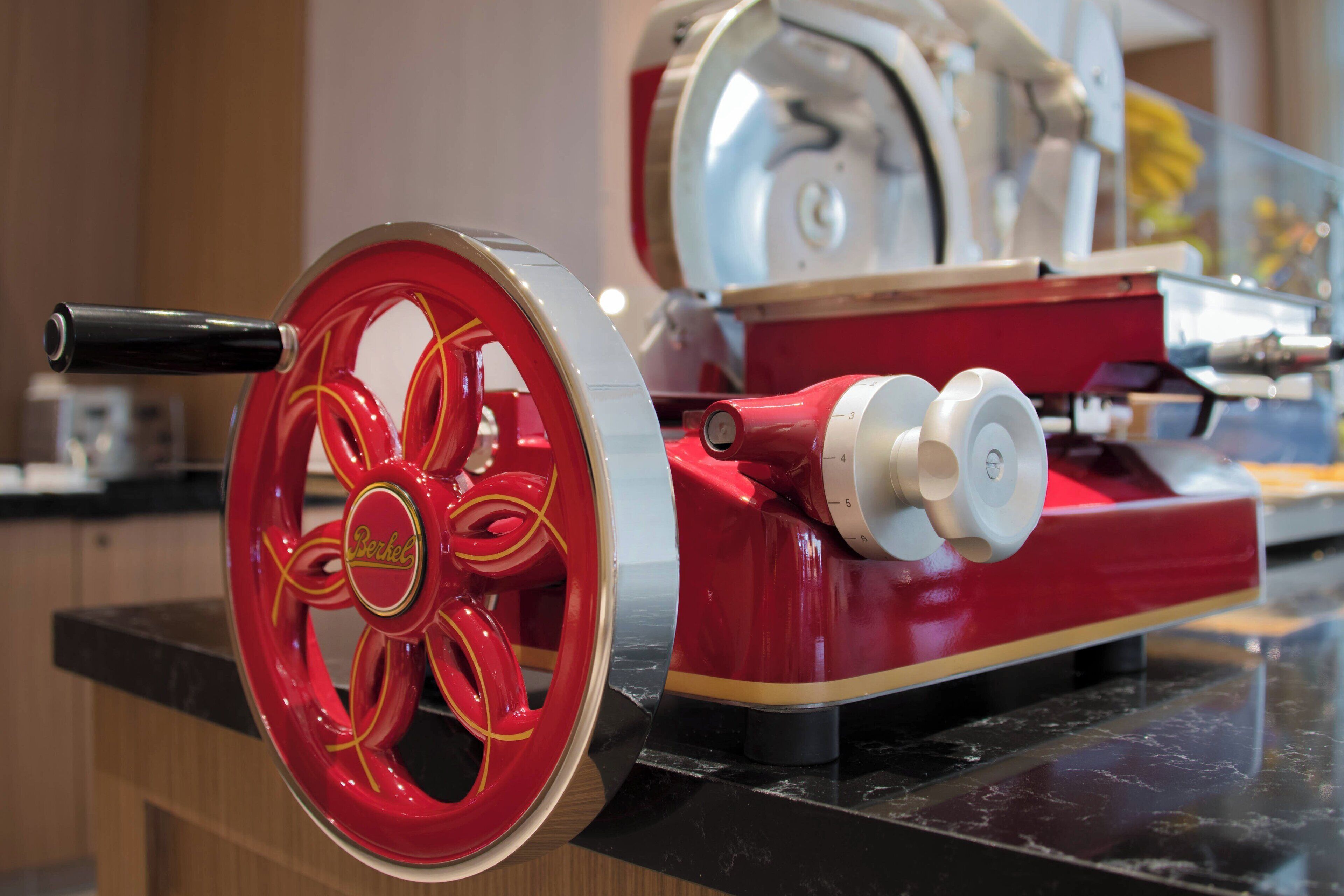 Ein Vintage-Mechanismus in Rot und Silber mit einem markanten Rad und Bedienelementen, vermutlich ein Stück historische Technik.