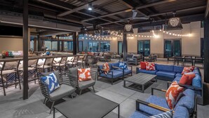 Un amplio espacio al aire libre con varios sofás y sillones, una barra y un gran ventanal con vistas a la ciudad.