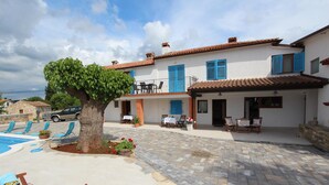 Une villa avec piscine, un espace extérieur aménagé et un grand arbre.