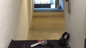 A hallway with a shooting range in the background, a pistol, and a pair of headphones on the floor. - Gasthaus Zur Einkehr (Neureichenau)