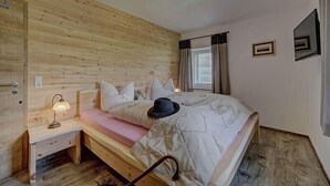 A wooden-paneled bedroom with a bed, bedside lamp, and a small nightstand. - Gasthaus Zur Einkehr (Neureichenau)