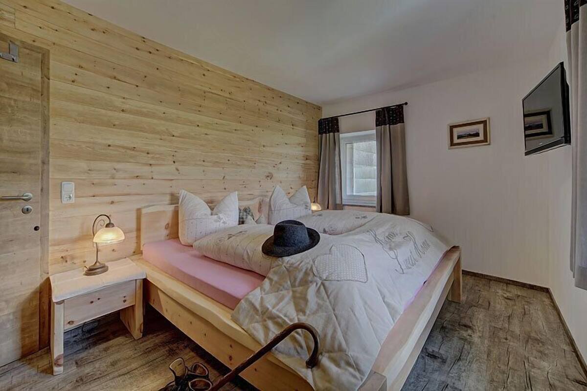 Quarto com painéis de madeira, cama, luminária de cabeceira e um pequeno criado-mudo.