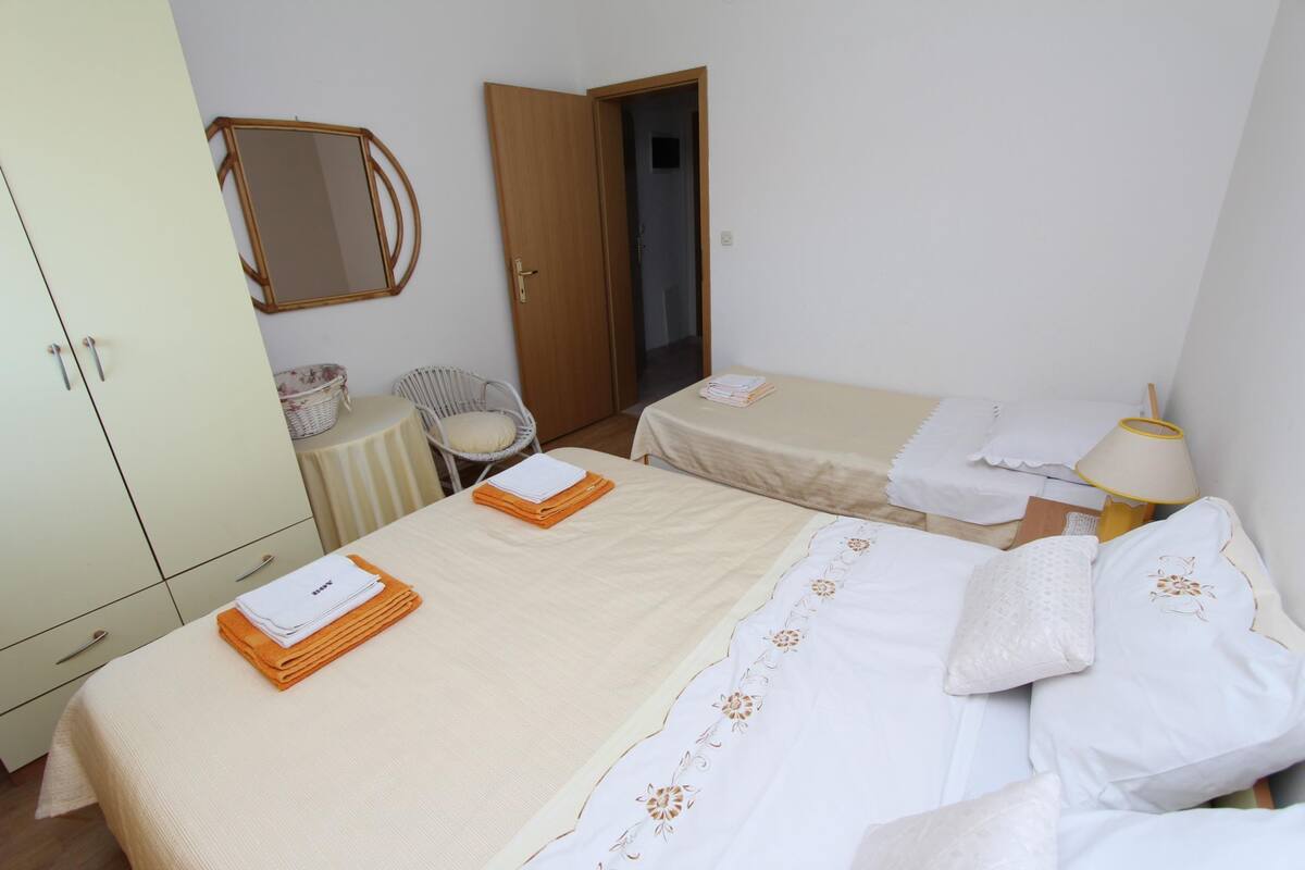Een hotelkamer met twee bedden, een garderobe, een stoel, een kleine tafel en een lamp.