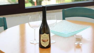 Una botella de vino sobre una mesa con dos copas y un cuenco de cristal.
