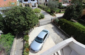 A residential area with a parked car, a gated entrance, and a staircase leading to a balcony. - Apartments Milena (Rovinj)