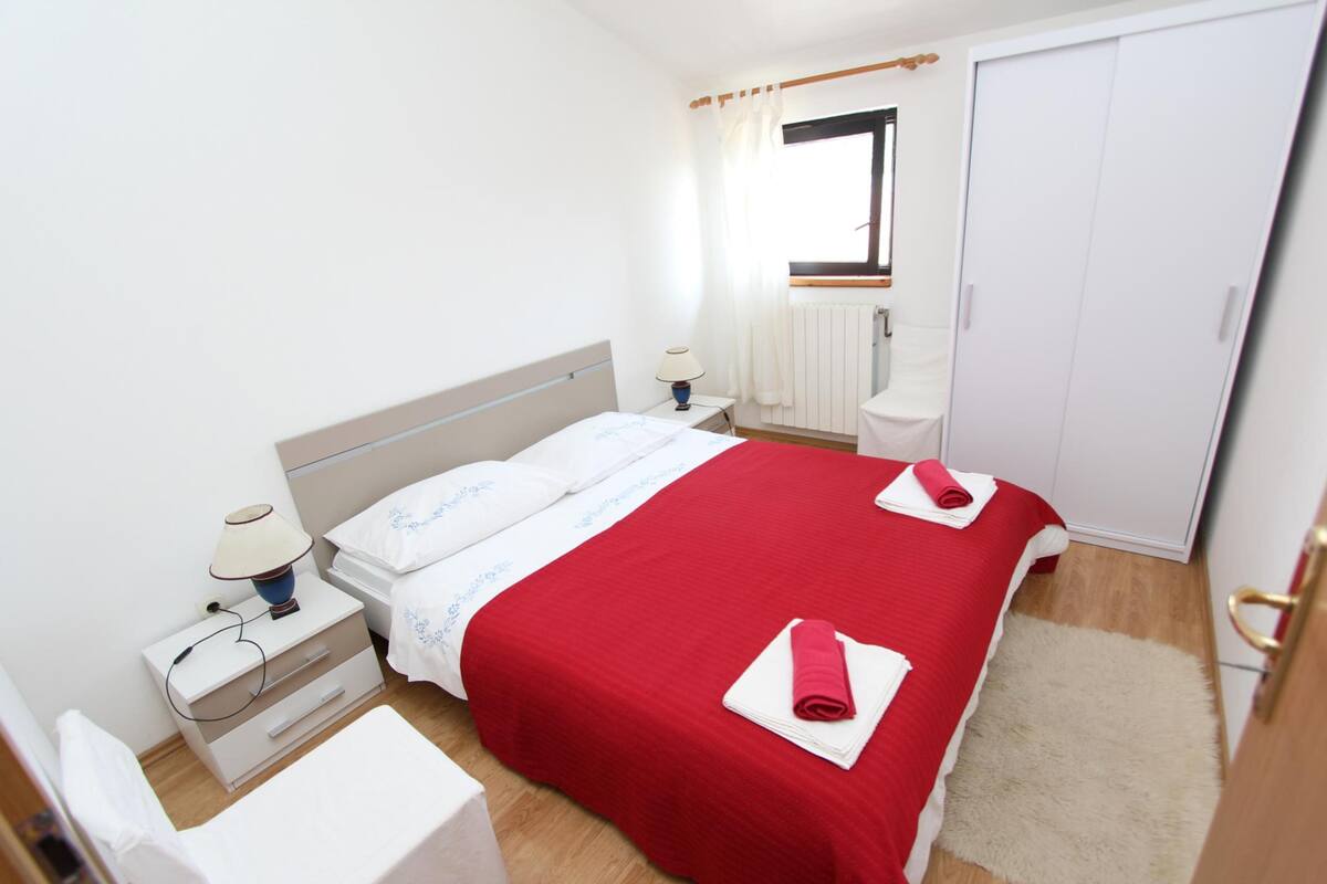 Een slaapkamer met een bed, nachtkastjes, een raam en een kledingkast.