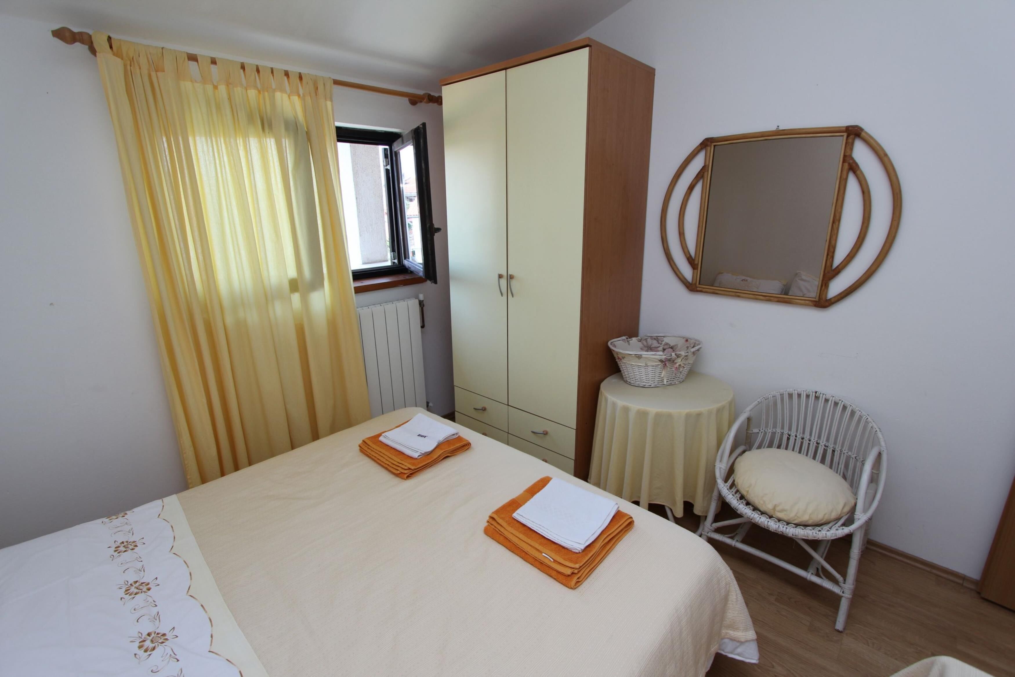 A bedroom with a bed, a wardrobe, a chair, and a small table with a basket.