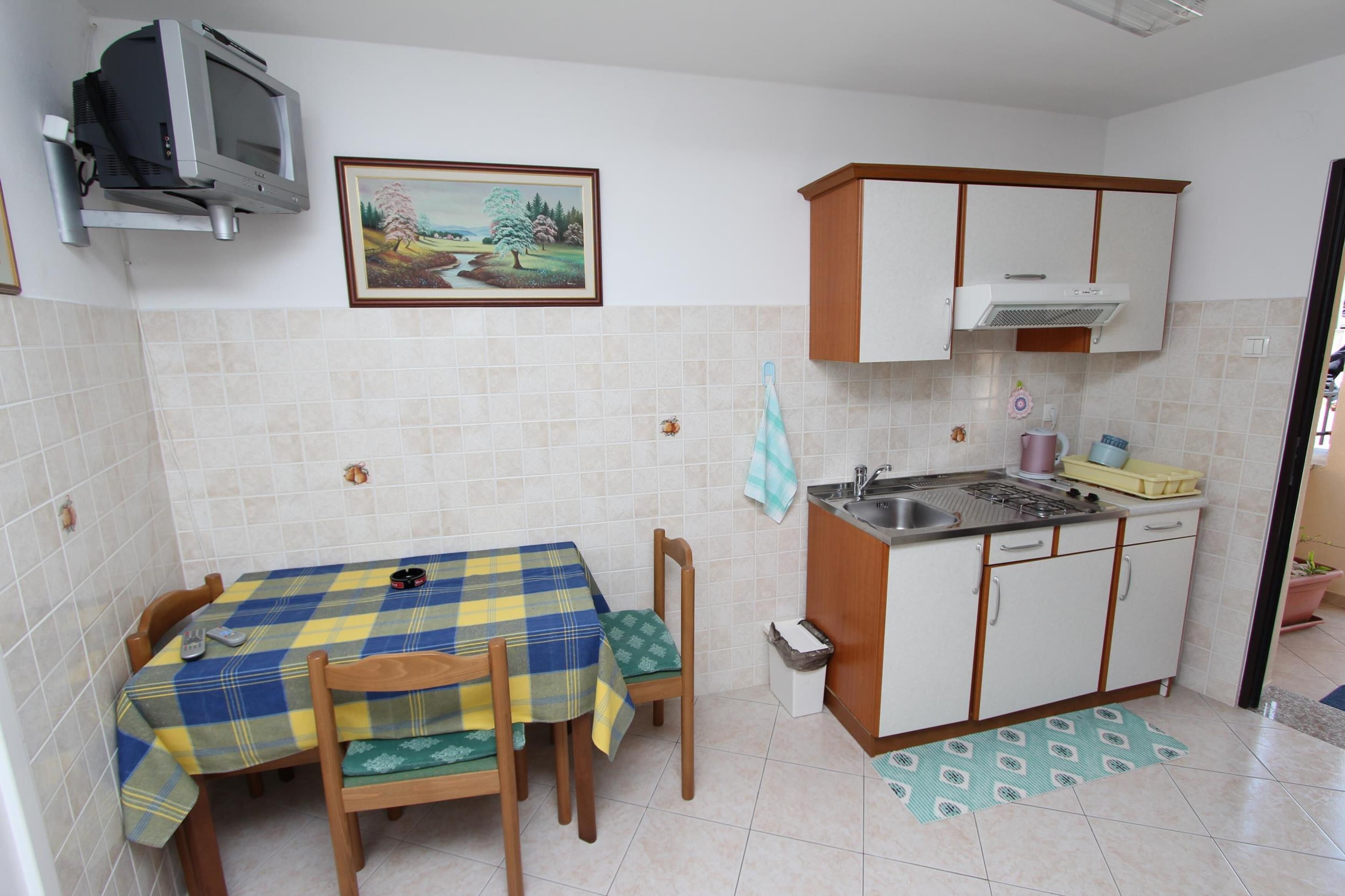A small kitchen with a dining table, chairs, a sink, and cabinets.