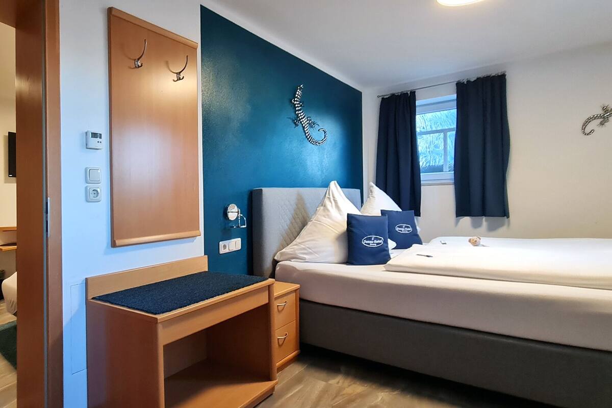 A hotel room with a bed, a desk, a chair, and a window with curtains.