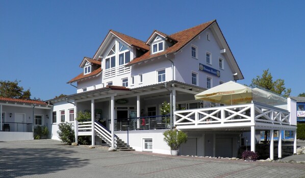 A two-story hotel with a balcony and a covered outdoor seating area. - Donauhotel (Sinzing)