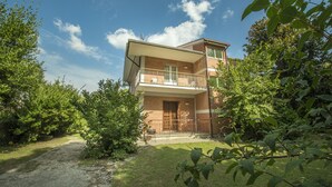 A two-story building with a balcony, surrounded by greenery. - Residenzadelia (Ronciglione)