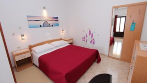 Un dormitorio con cama, mesita de noche, cómoda, espejo y un cuadro colgado en la pared.