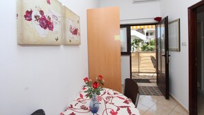 Un comedor con una mesa dispuesta para dos, un florero con flores y vistas a un balcón con barandilla.