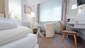 Une chambre d’hôtel équipée d’un lit, d’un bureau, d’une chaise, d’une table et d’un téléviseur.