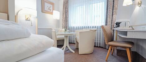 Una habitación de hotel con cama, escritorio, silla, mesa y televisor.