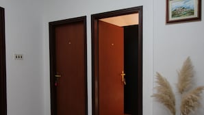 A hallway with two wooden doors, a wall-mounted light switch, and a framed picture. - Guests House Sanja (Rovinj)