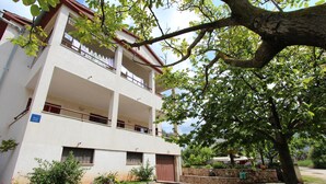 A two-story building with a stone facade, a gated entrance, and a small garden area with potted plants. - Guests House Sanja (Rovinj)