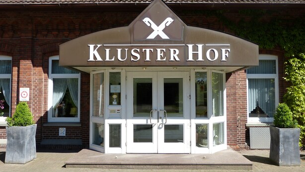 A brick building with a sign reading "Kluster Hof" above the entrance. - Kluster Hof (Basdahl)