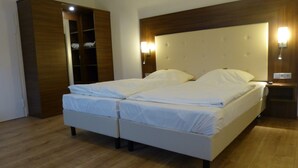A double bed with white linens, a wooden wardrobe, and a nightstand with a lamp. - Kluster Hof (Basdahl)