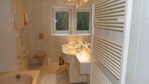 A modern bathroom with a toilet, sink, and bathtub. - Kluster Hof (Basdahl)