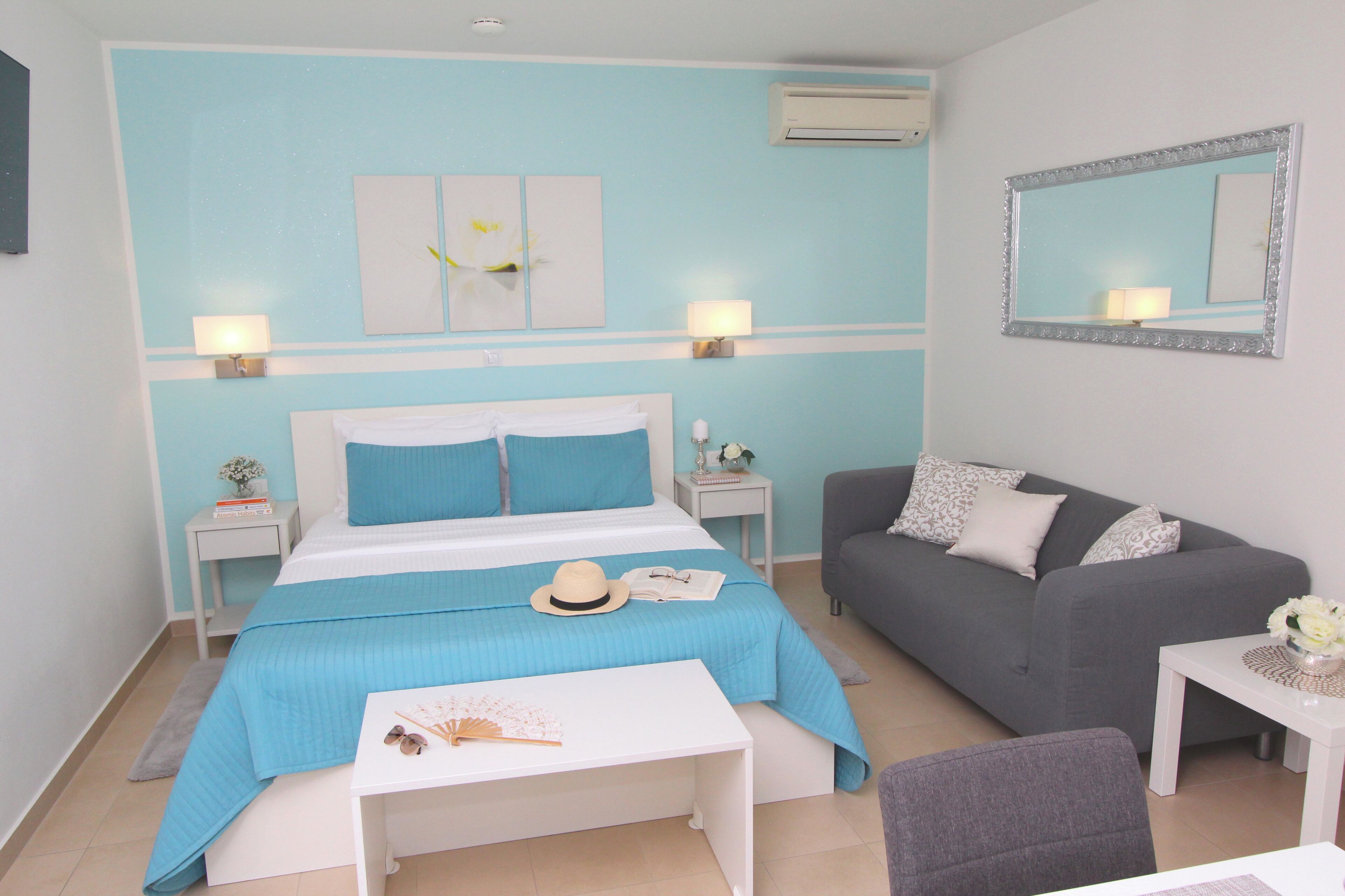 A bedroom with a bed, bedside tables, a sofa, a small table, and a mirror.
