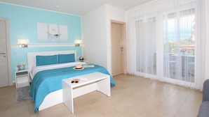 Un dormitorio con cama, mesitas de noche, cortinas transparentes en la ventana y vistas al exterior.