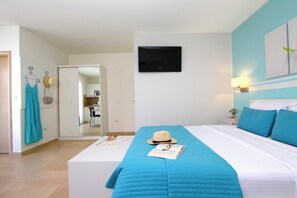 A bedroom with a bed, a bedside table, a wall-mounted TV, and a door leading to a bathroom. - Studio Emanuel (Rovinj)