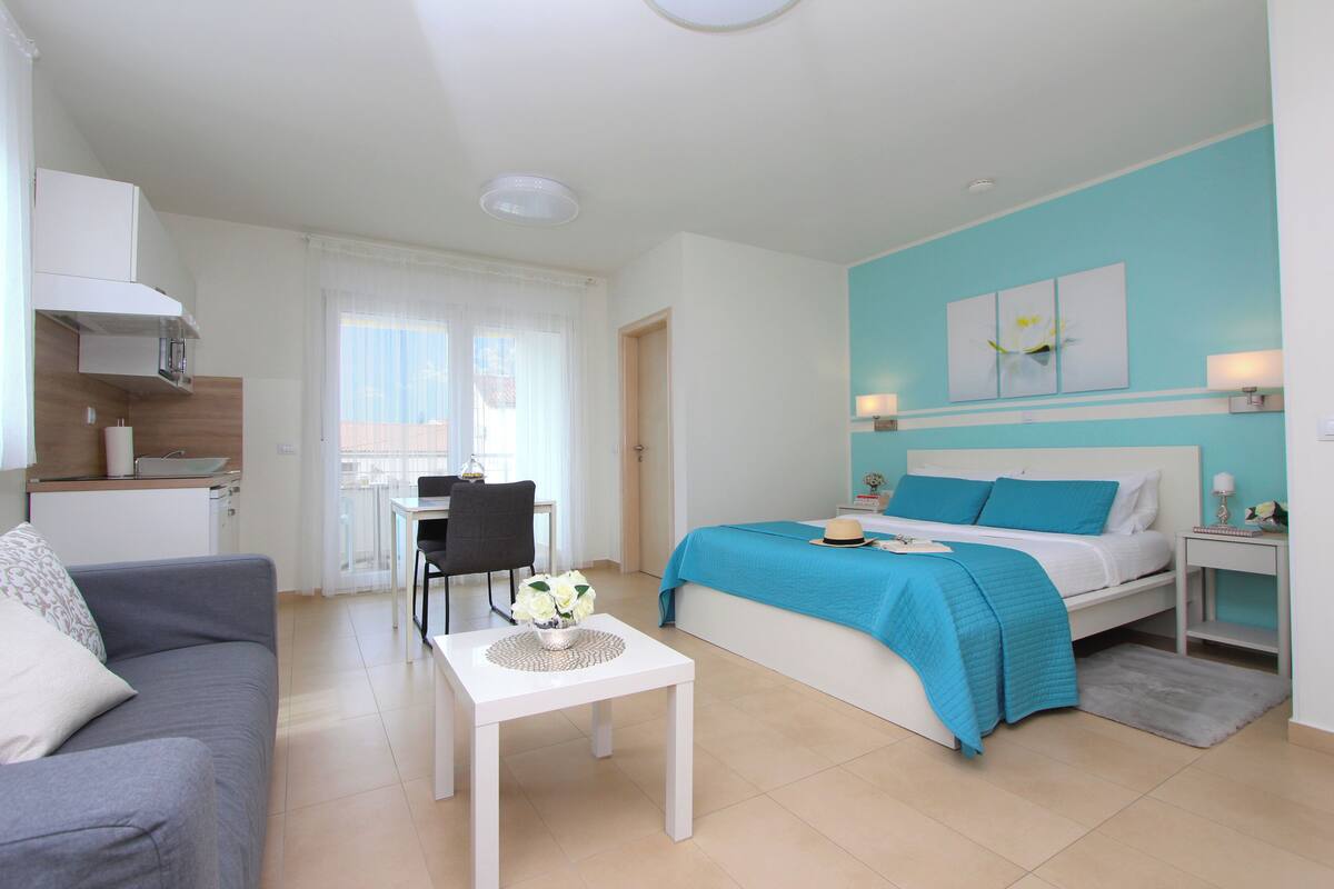 Une chambre d’hôtel moderne équipée d’un lit, d’un bureau, d’un canapé et d’une kitchenette.