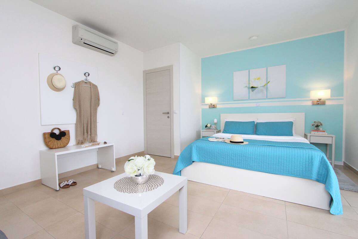 Une chambre à coucher comprenant un lit, des tables de chevet, un bureau et un appareil de climatisation.