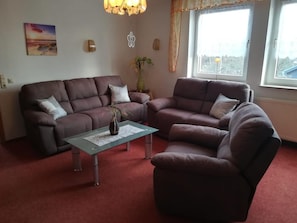 A living room with two sofas, a coffee table, and a window with curtains. - Kyffhaeuser Goldene AUE (Wallhausen)