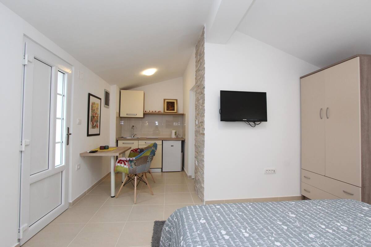 A compact room with a bed, a desk, a chair, a television, and a wardrobe.