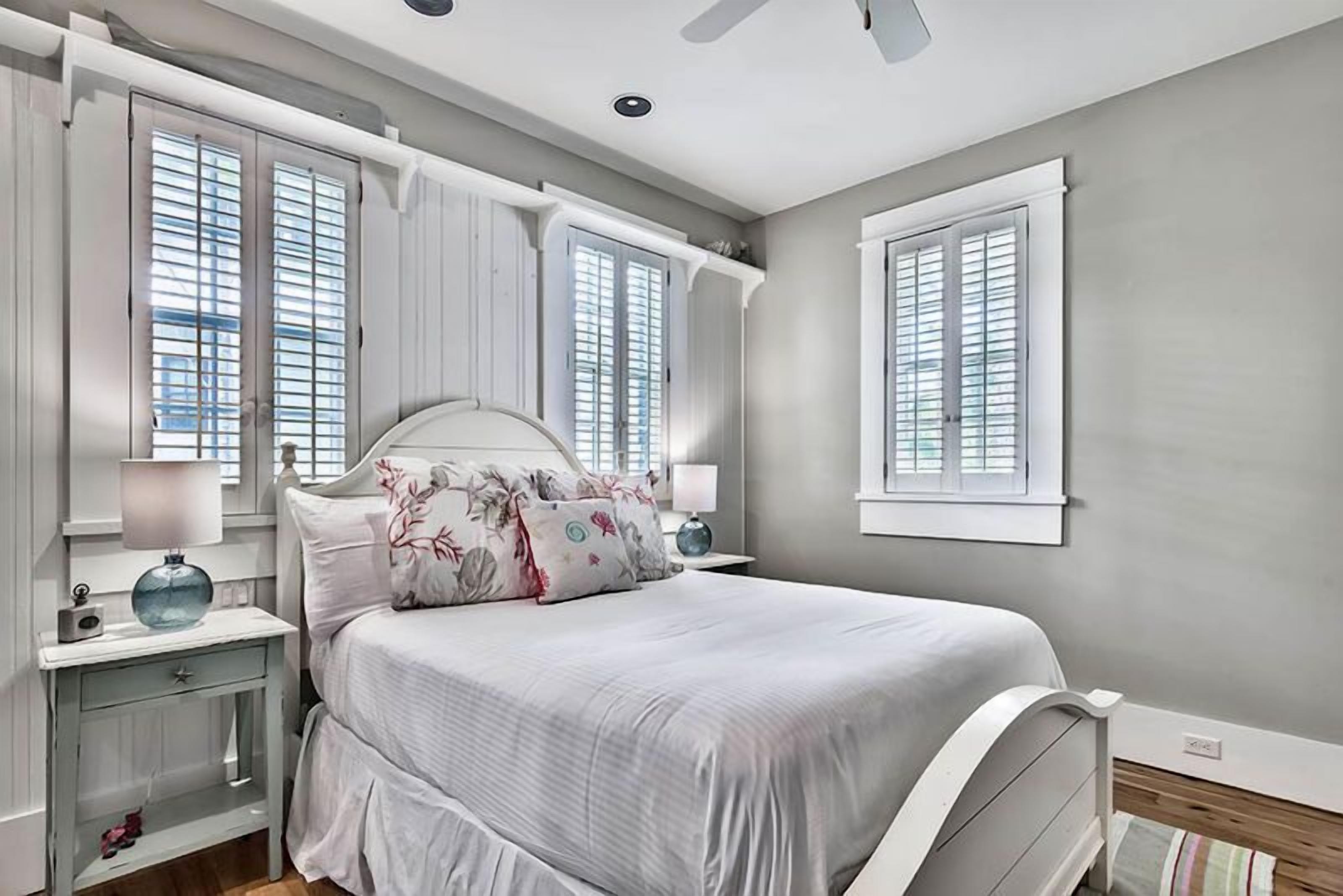 Quarto com cama, mesas de cabeceira e ventilador de teto.