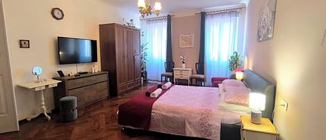 A bedroom with a bed, bedside tables, a TV, a wardrobe, a desk, and a chair.
