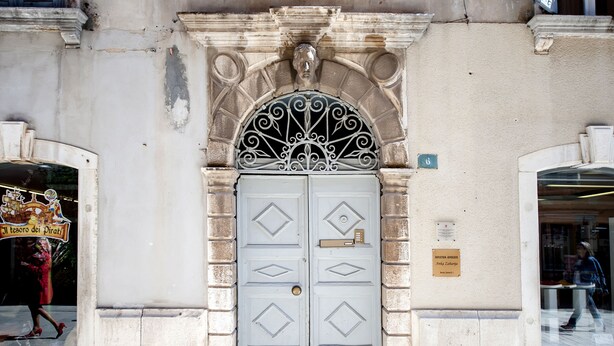 Une façade d’immeuble ornée d’une grande porte décorative, d’une plaque et d’une enseigne placée au-dessus de la porte.