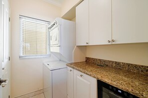 A laundry room with a washing machine, dryer, and stacked cabinets.