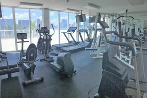 Un gimnasio con máquinas de cardio, máquinas de pesas y un amplio ventanal con vistas a la ciudad.