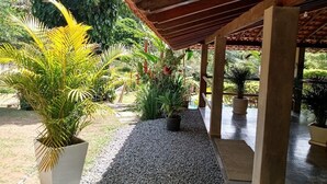 A covered outdoor area with a gravel path, potted plants, and a wooden pergola structure. - Amazing house in the mountains in a gated community, lots of privacy - Paty do Alferes (Paty do Alferes)
