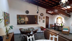 A cozy living room with a round glass table, a brown leather sofa, and a dining area with wicker chairs. - Amazing house in the mountains in a gated community, lots of privacy - Paty do Alferes (Paty do Alferes)