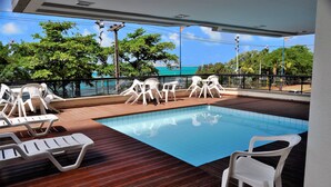 A pool area with white plastic chairs and a wooden deck. - SEAFLATS Villa Costeira (Fortaleza)