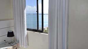 A room with a view of the sea through a window with white curtains. - SEAFLATS Villa Costeira (Fortaleza)