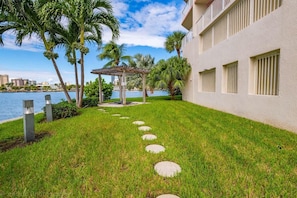 Relax in a serene outdoor space with a lawn, stepping stones, and a covered seating area.