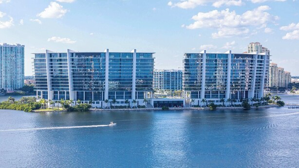 A high-rise hotel with multiple floors, a waterfront view, and a pool area.
